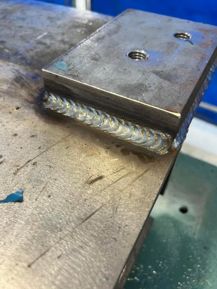 A stacked weld bead joining a steel plate to a bench top